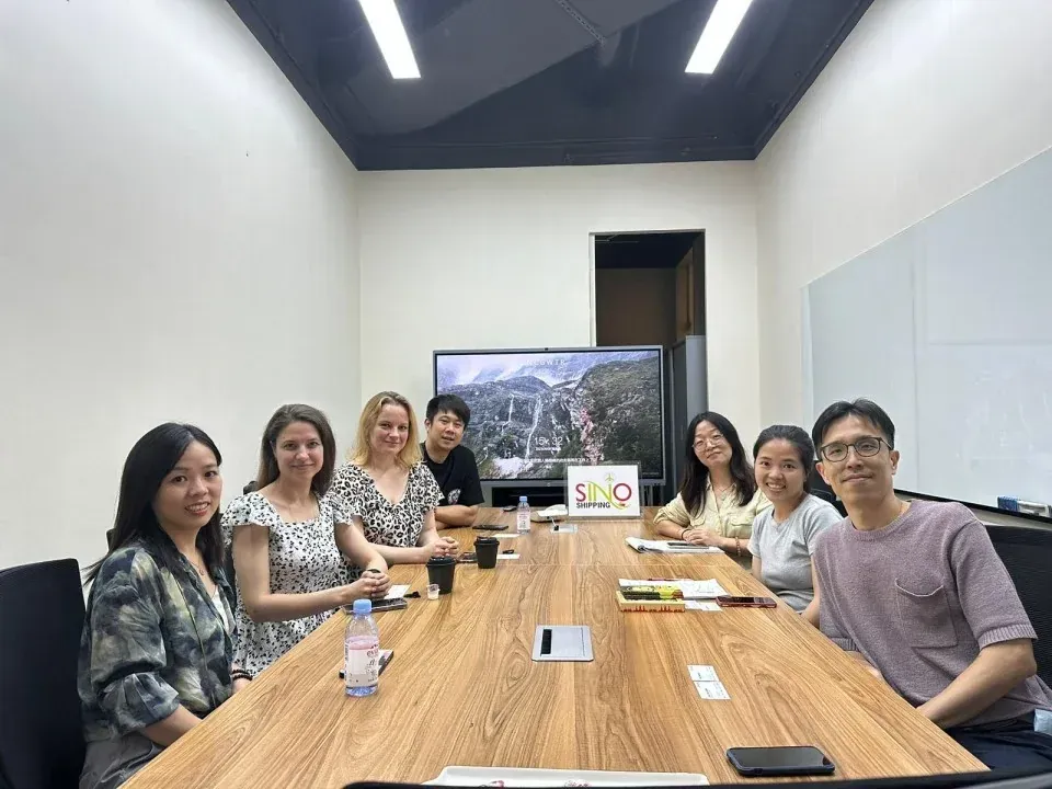 Recibimiento de clientes internacionales alrededor de la mesa con branding.