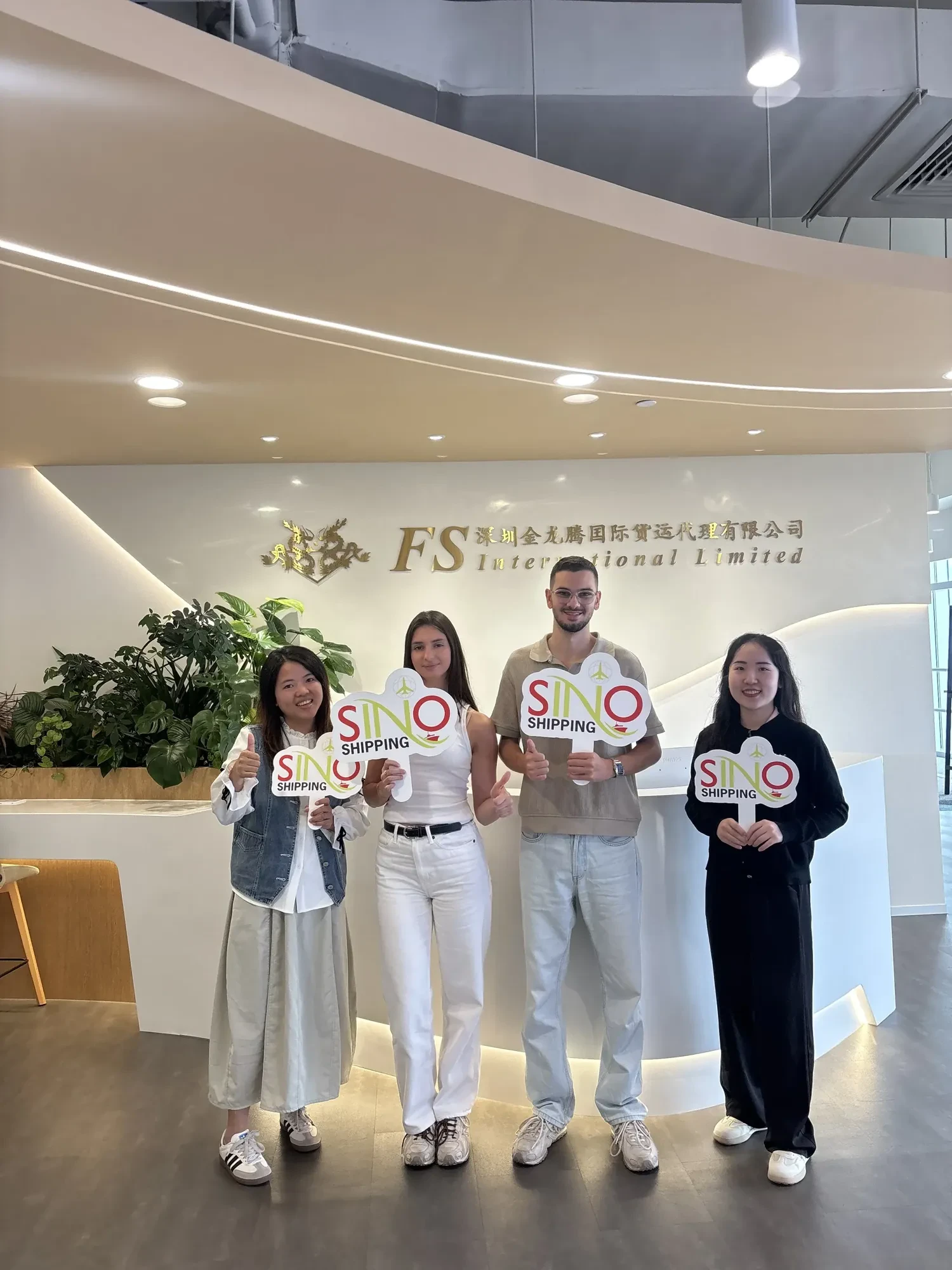 Foto con Rayan y Chloe sosteniendo paddles SINO en nuestra oficina de Shenzhen.