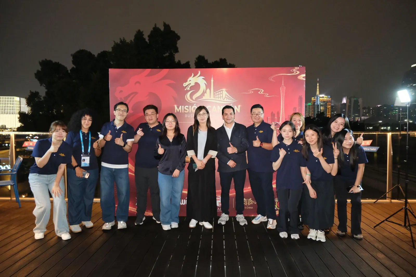 Equipe da Missão Cantão 2026 reunida à noite em Guangzhou diante de um painel da missão
