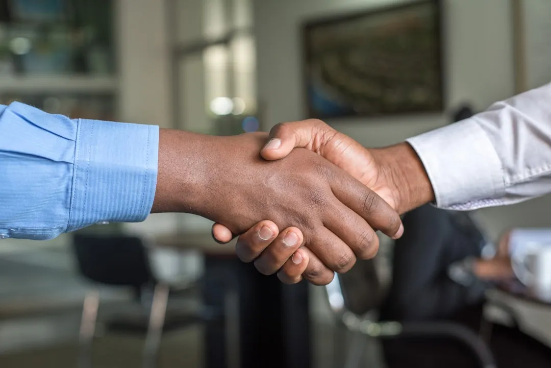 Dos personas dándose la mano sobre un documento