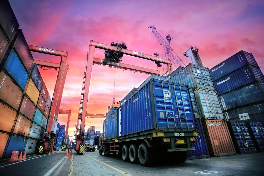 Contenedores de transporte apilados en un puerto concurrido al atardecer