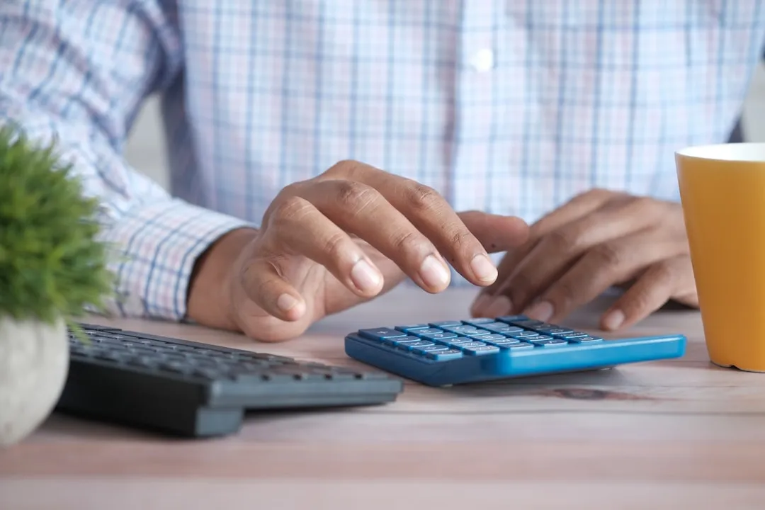 Persona usando una calculadora en un escritorio para calcular impuestos