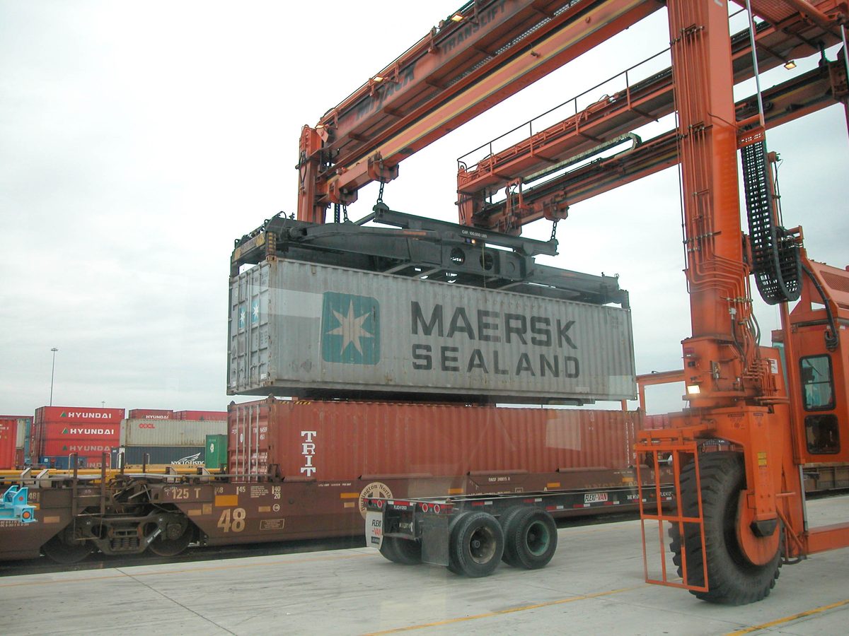 Guindaste pórtico carregando um contêiner de 40 pés em um vagão ferroviário no terminal intermodal