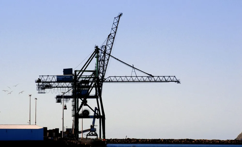 Silueta de grúa portuaria al atardecer en una terminal de contenedores