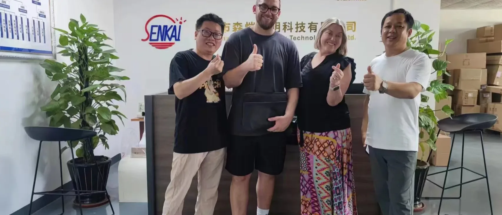 Agente de abastecimiento inspeccionando productos con un proveedor en un showroom de fábrica en China, con contenedores de envío visibles a través de la ventana