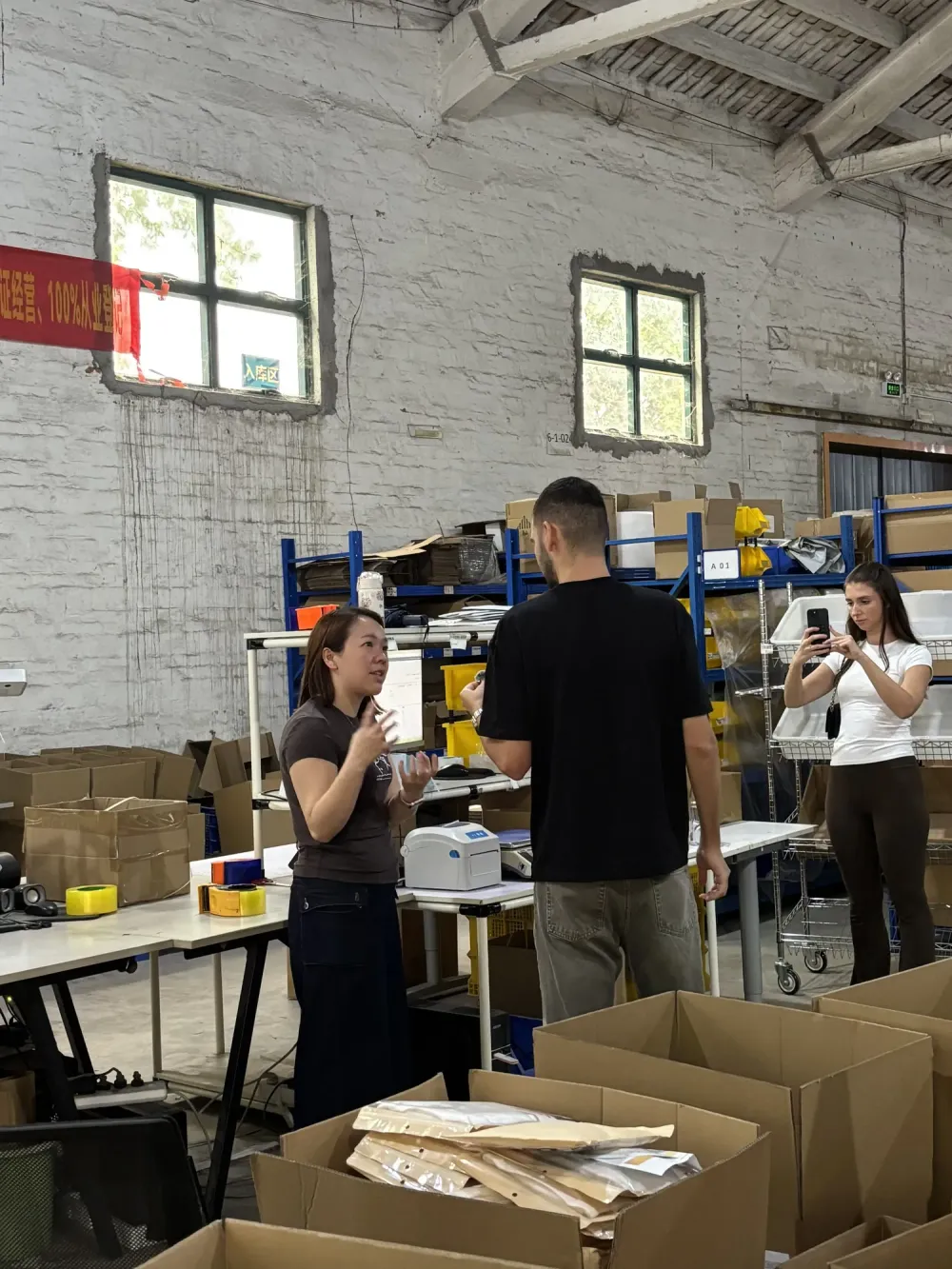 Clientes recorriendo el almacén de consolidación de SINO entre estanterías azules cargadas de cajas