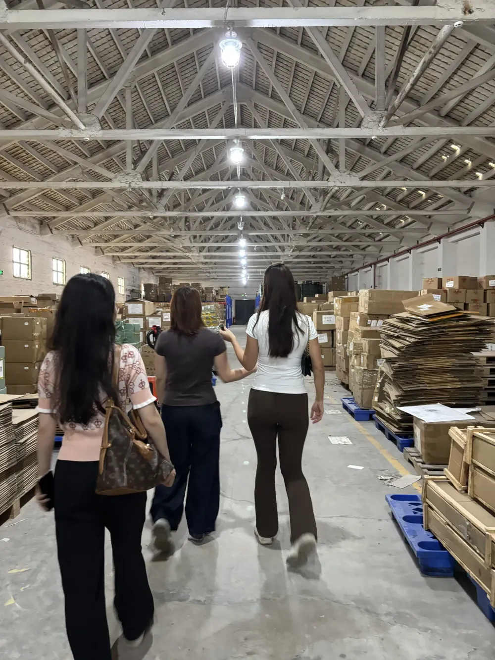 Clientes recorriendo un pasillo del almacén de SINO Shipping entre estanterías cargadas de cajas